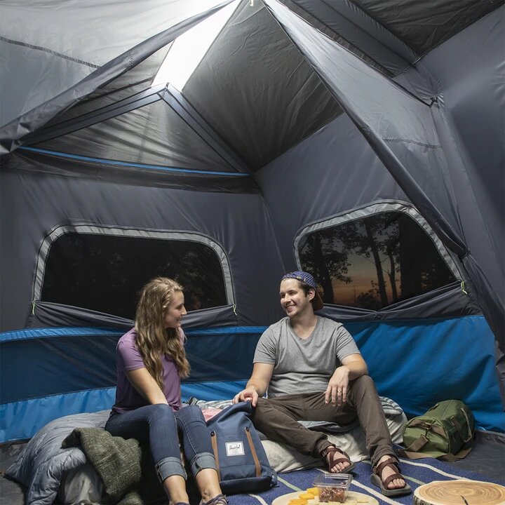 A large, orange and gray CORE 10-person instant tent with a lighted screen room. The tent has a spacious interior and multiple windows, providing ample ventilation and natural light.